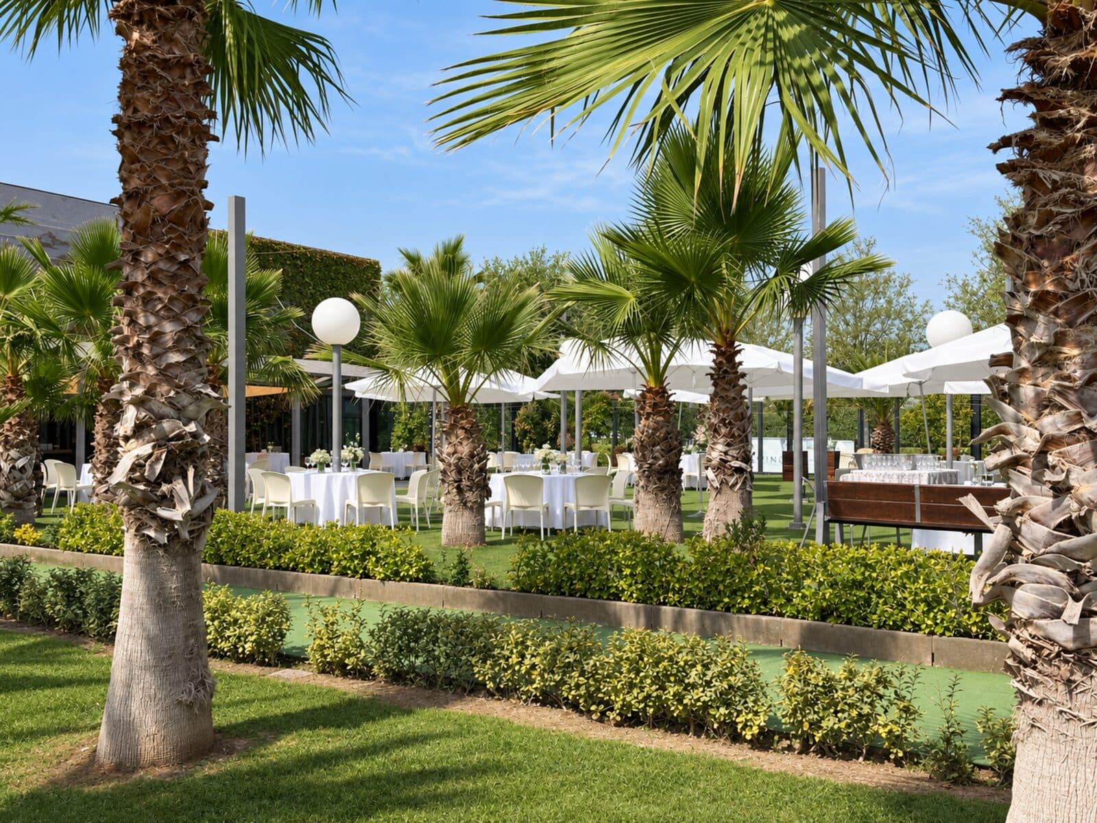 Jardines de Espacio Ebro, con la alameda de palmeras y las mesas del aperitivo al aire libre