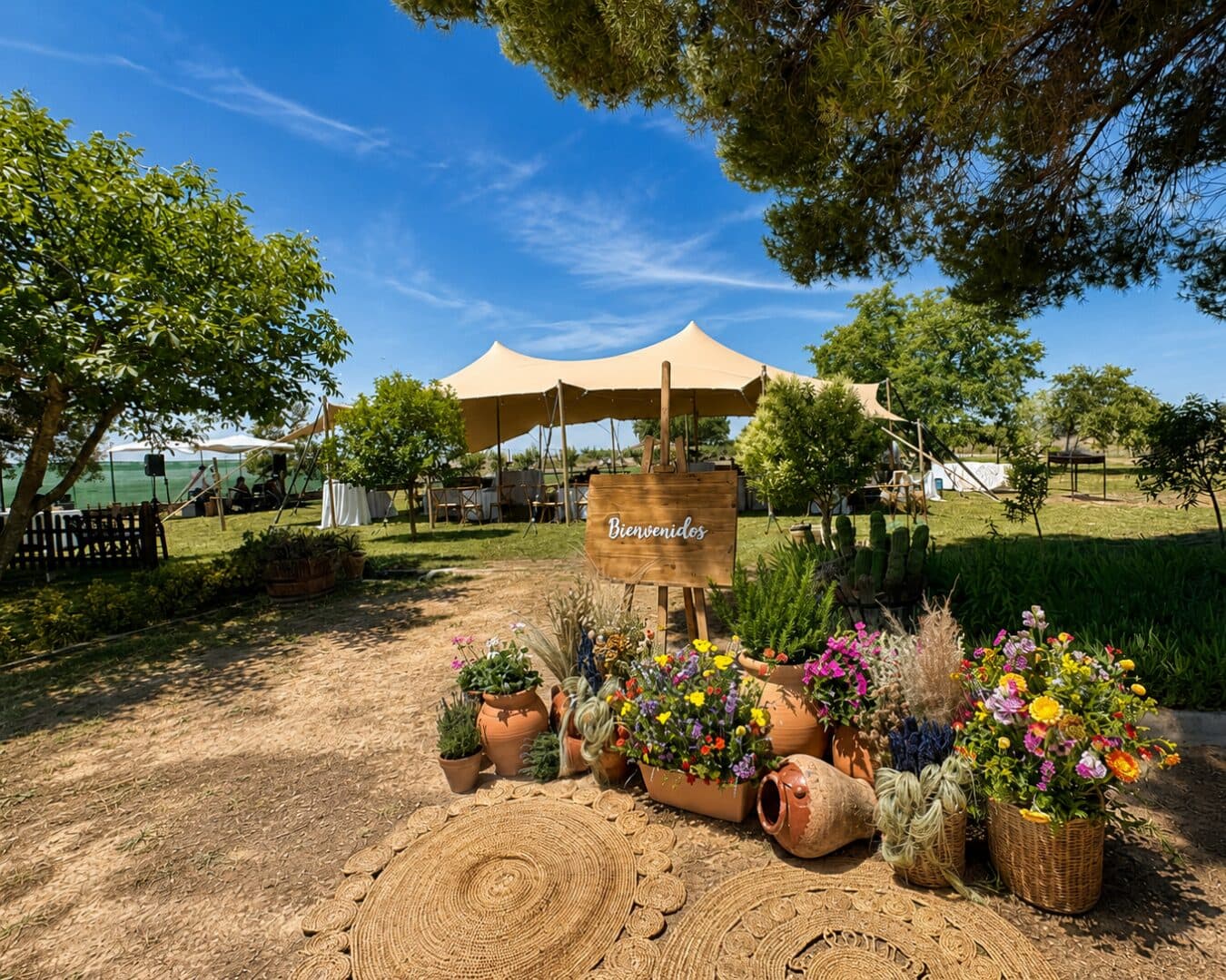 Rincón de bienvenida con flores y alfombras de esparto en un jardín